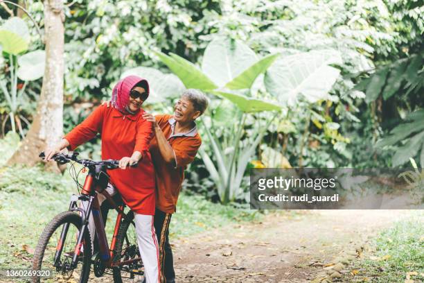 asian senior woman on bike in forest - passenger train stockfoto's en -beelden