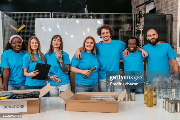 smiling volunteers in charity donation center - volunteers stock pictures, royalty-free photos & images