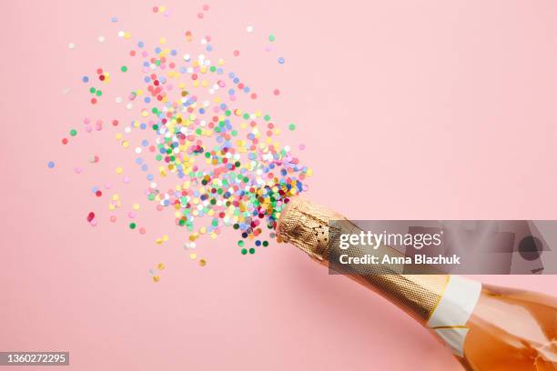 champagne bottle and colorful shiny confetti over pink, trendy greeting card for holidays and celebrations. - birthday flag stock-fotos und bilder