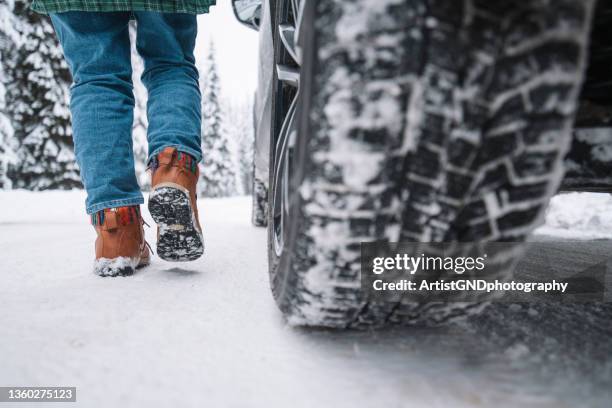 low section of woman walking on snowy road next to vehicle - naast stockfoto's en -beelden