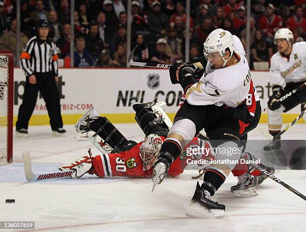 Andrew Cogliano of the Anaheim Ducks tries to get off a shot against Ray Emery of the Chicago Blackhawks after being hooked by Nick Leddy from behind...