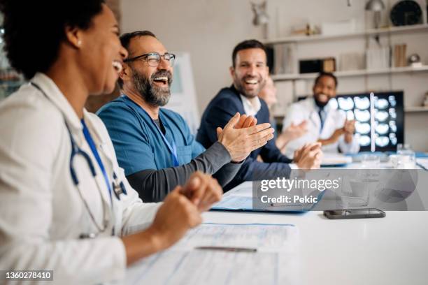 group of doctors applauding while attending healthcare seminar - persconferentie stockfoto's en -beelden