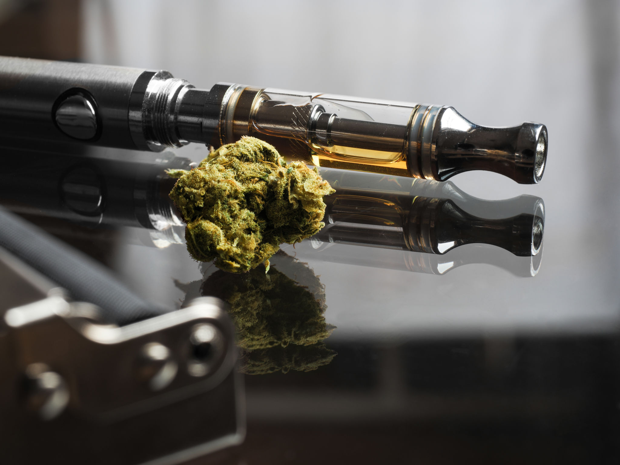 Close up shot of real cannabis or weed with cannabis oil in cartridge of vape pen in the background, roller blurred in foreground and text space on the right under the dark theme Close up shot of real cannabis or weed with cannabis oil in cartridge of vape pen in the background, roller blurred in foreground and text space on the right under the dark theme