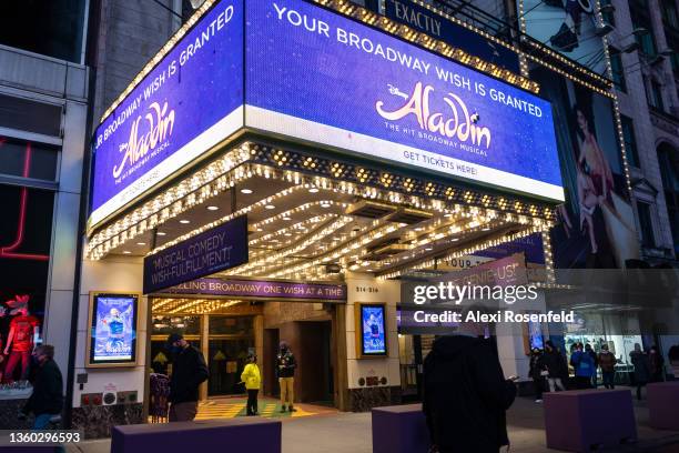 People walk past the New Amsterdam Theatre home to "Aladdin" which has postponed shows due to COVID-19 outbreaks on December 21, 2021 in New York...