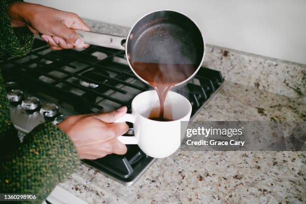 woman pours hot chocolate into mug - winter cooking stock pictures, royalty-free photos & images