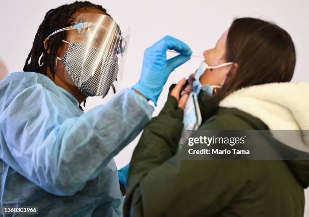 Merline Jimenez administers a COVID-19 nasopharyngeal swab to a person at a testing site located in the international terminal at Los Angeles...
