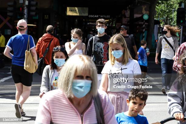 People wearing face masks cross Collins Street on December 22, 2021 in Melbourne, Australia. Victoria's COVID-19 case numbers are on the increase...