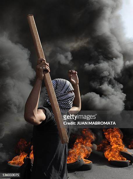 Demonstrator holds a stick next to burning tires blocking 9 de Julio Avenue in downtown Buenos Aires on December 20 during a protest for the 10th...
