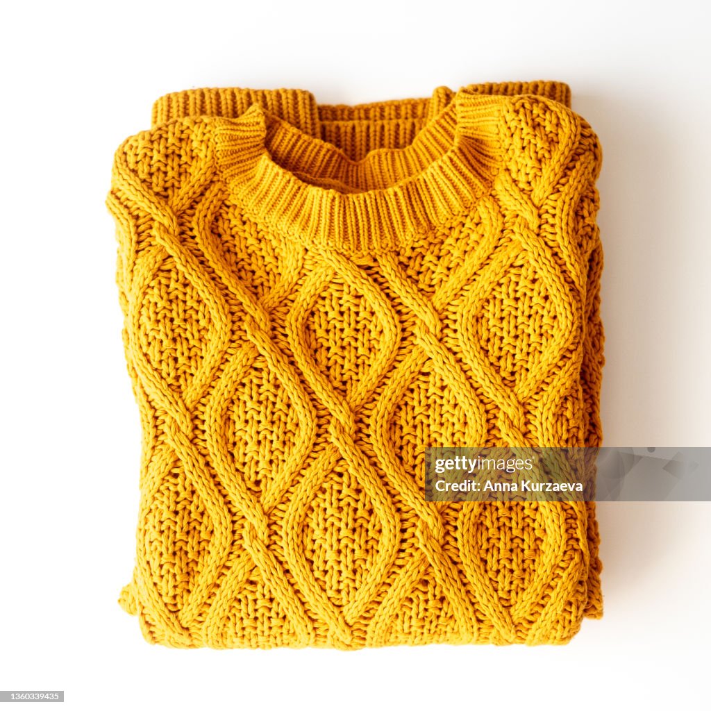 Folded yellow sweater on a table, top view
