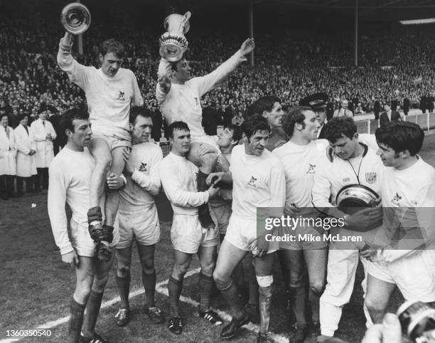 West Bromwich Albion football club team captain Graham Williams holding the trophy aloft and Clive Clark holding the lid are carried on the shoulders...