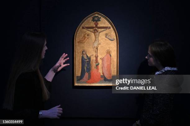 Gallery assistants pose next to "The Crucifixion with the Virgin, Saint John the Baptist and the Magdalen at the Foot of the Cross" painting by...