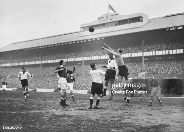 German national team goalkeeper Hans Jakob jumps to punch the ball clear from a crowded penalty area over team mate and defender Ludwig Goldbrunner...