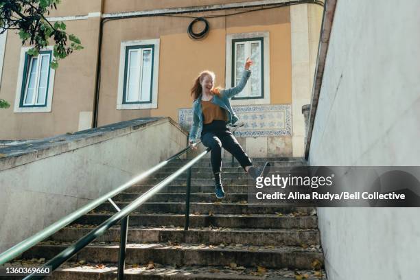 Young woman sliding down a stair railing