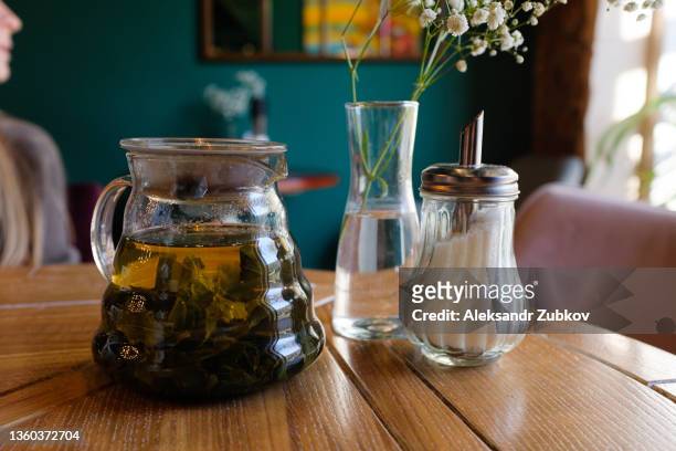 an antique wooden table, a sofa, a bouquet of flowers in a stylish vase and a sugar bowl and a teapot for brewing tea. preparation for the event, coffee break. stylish, fashionable, modern design of a cafe, restaurant, cafeteria or pizzeria. - sugar bowl crockery stock pictures, royalty-free photos & images