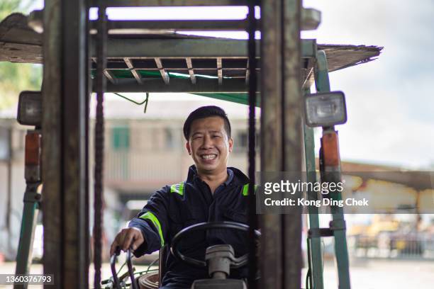 asian chinese man worker smiling looking at camera on forklift working. - camera operator stock pictures, royalty-free photos & images