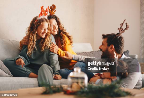 a happy family is enjoying during the winter holidays. parents and two kids are playing and smiling. - happy holidays family stock pictures, royalty-free photos & images