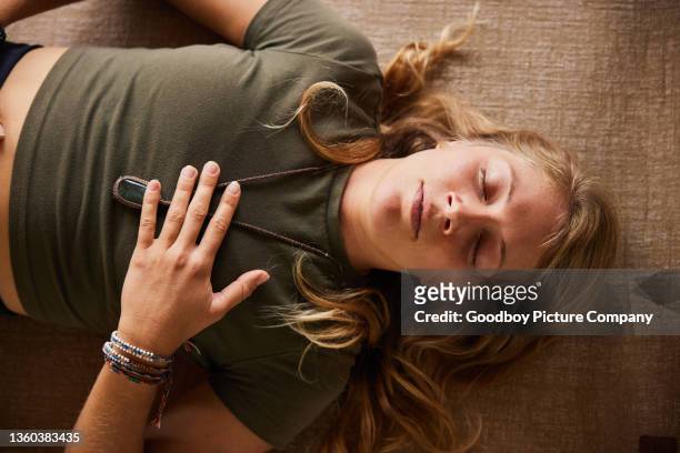 young woman in sportswear doing breathing exercises on a yoga mat - reclining stockfoto's en -beelden
