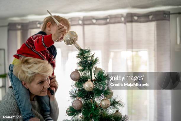 mother decorating christmas tree with her son - baby winter farm son stock pictures, royalty-free photos & images