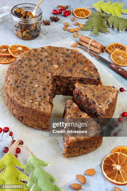 imagen de pastel de frutas de navidad en rodajas, casero, en papel de pergamino a prueba de grasa, cuchillo, paquetes de palitos de canela, frasco de carne picada, árboles de navidad de fieltro, anís estrellado, almendras, cítricos secos de naranja, bay - aguja parte de planta fotografías e imágenes de stock