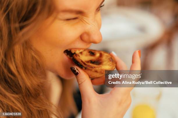 close-up of a young woman biting into pastel de nata - pastel de nata stock pictures, royalty-free photos & images