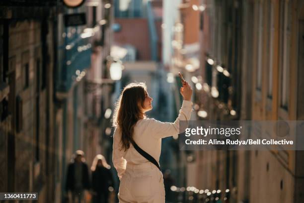 Woman taking a picture with her smartphone in a narrow downtown street
