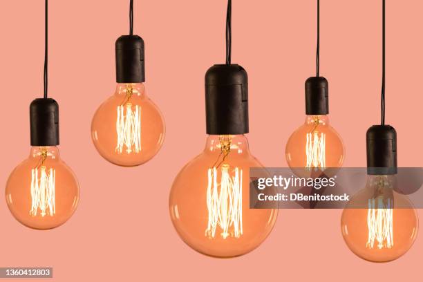 five glowing vintage incandescent filament bulbs, hung at different heights, on pink background. concept of light bulbs, ideas, electricity, electricity bill and electricity prices. - number 5 stock pictures, royalty-free photos & images