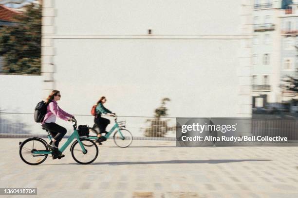 two women biking in a city - bike sharing stock-fotos und bilder