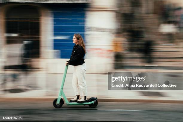 woman driving an electric scooter in a city - sparkcykel bildbanksfoton och bilder