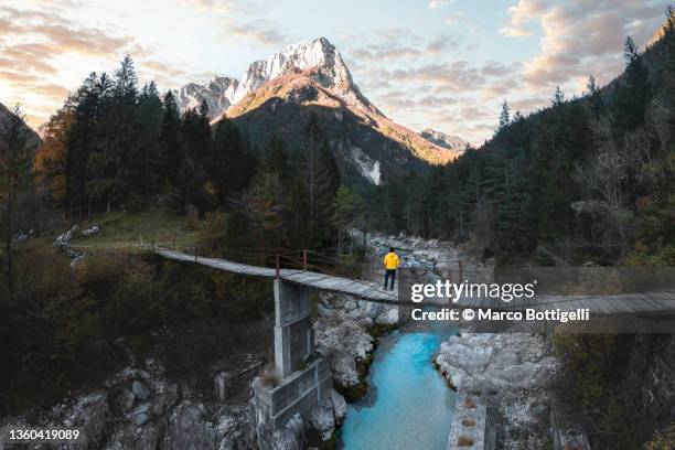 man standing on a suspension bridge above a mountain river - people above park stock pictures, royalty-free photos & images
