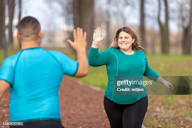 people with overweight problem running in city park - overweight stockfoto's en -beelden