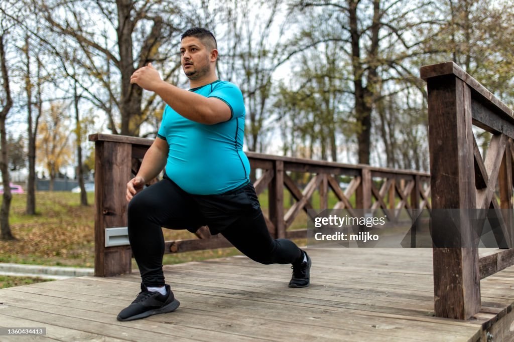 Man with overweight problem exercising in city park
