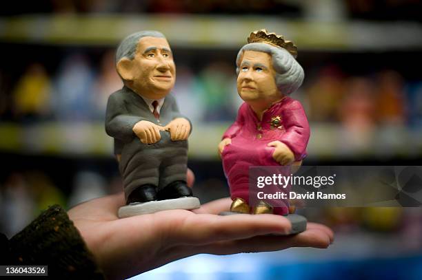 Stallholder holds two traditionally styled 'caganer' of Prince Charles, Prince of Wales and Queen Elizabeth II at a christmas items shop on December...