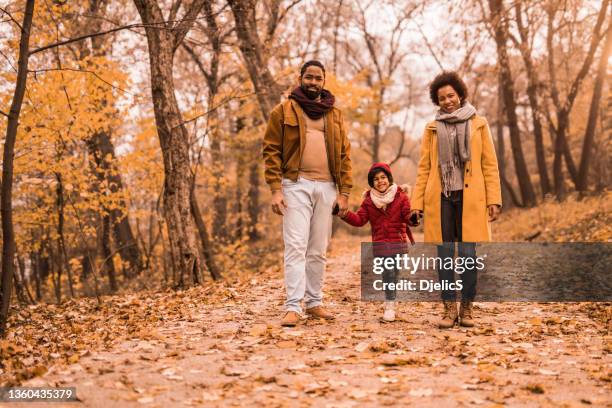 秋の公園を歩き、カメラを見ているアフリカ系アメリカ人の家族。 - african american couple walking park ストックフォトと画像