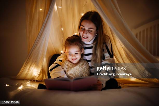 mother and child reading book in bed before going to sleep - nursery night stock pictures, royalty-free photos & images