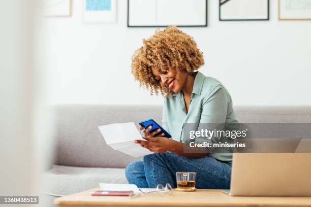 home office: una mujer afroamericana usando un teléfono móvil - invoice fotografías e imágenes de stock