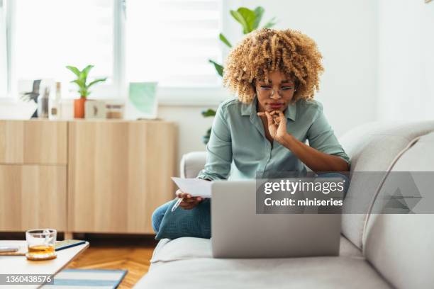 home office: an afro-american woman looking at a laptop - women on laptop stock pictures, royalty-free photos & images