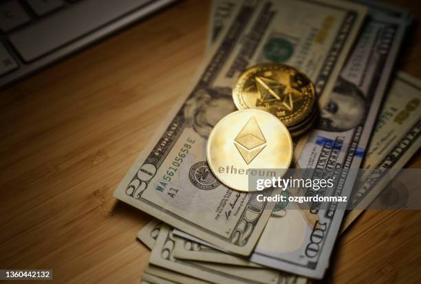 close up of ethereum golden coins on us dollar bills with spotlight on the ethereum in the foreground. - ethereum stockfoto's en -beelden