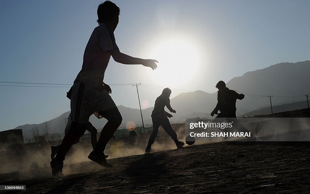 Afghan boys play football in a field in