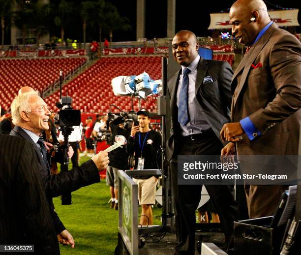 Dallas Cowboys owner and GM Jerry Jones, left, jokes with former Cowboy player Deion Sanders, right, as former player Marshall Faulk, middle, looks...