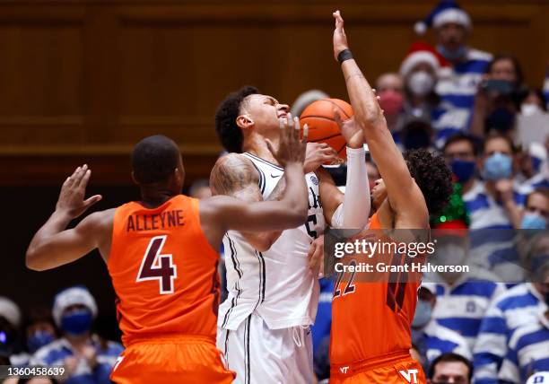 Paolo Banchero of the Duke Blue Devils loses the ball as he drives between Nahiem Alleyne and Keve Aluma of the Virginia Tech Hokies during the first...