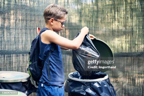 adolescente llevando basura a cubo de basura - quitar fotografías e imágenes de stock