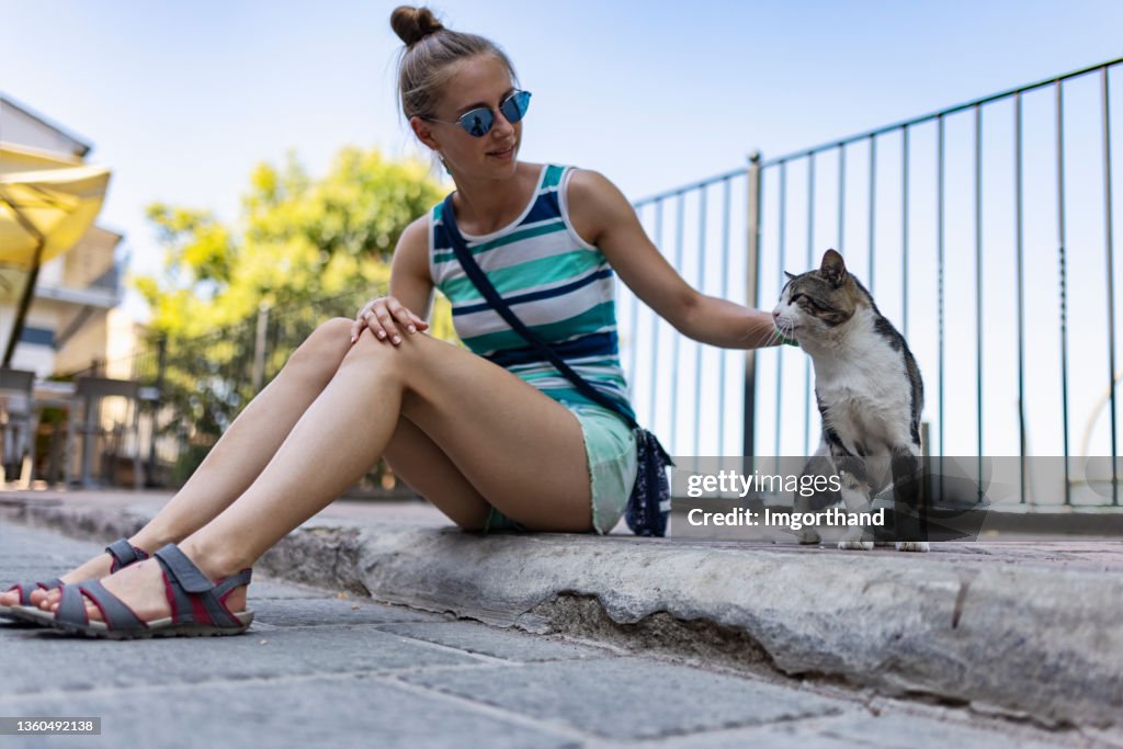 Teenage girl petting street cat in the small Italian town