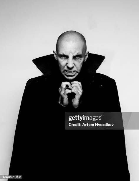 studio portrait of sinister vampire in cloak - vampir stock-fotos und bilder