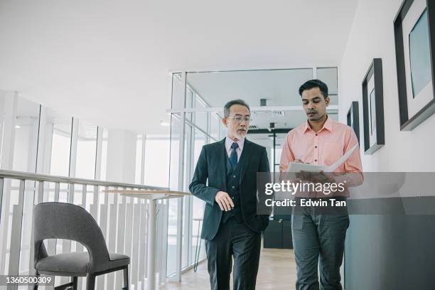 asian chinese ceo walking in corridor at his office giving order to his male secretary - allowing stockfoto's en -beelden