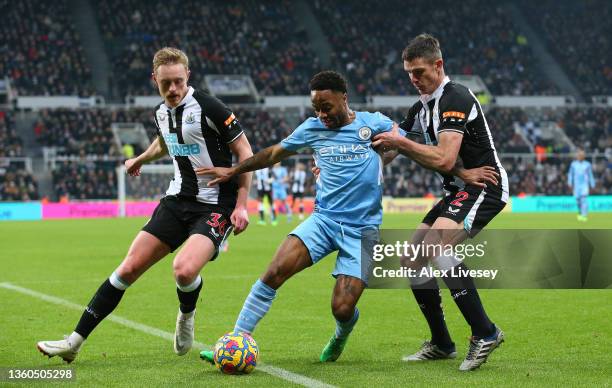 Raheem Sterling of Manchester City holds off a challenge from Ciaran Clark and Sean Longstaff of Newcastle United during the Premier League match...