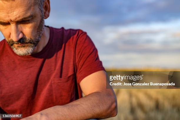 besorgter und ernster mann mittleren alters schaut auf den boden. sonniger nachmittag. madrid, spanien - concerned farmers stock-fotos und bilder