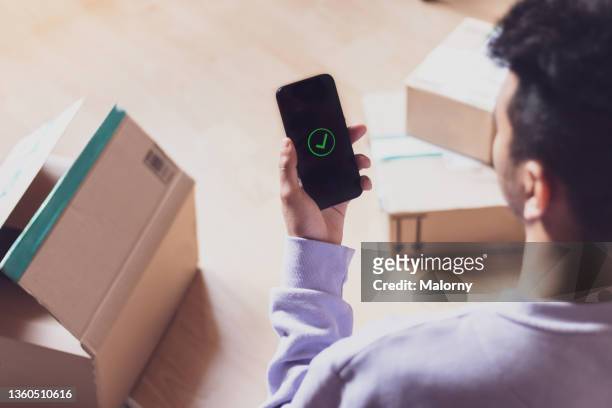 young man receiving packages. delivery confirmation. - debit cards credit cards accepted stock pictures, royalty-free photos & images