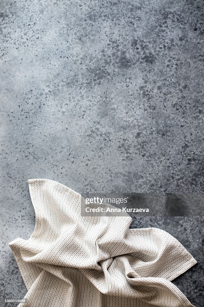 White and black linen striped napkin folded on grey concrete background, top view. Copy space