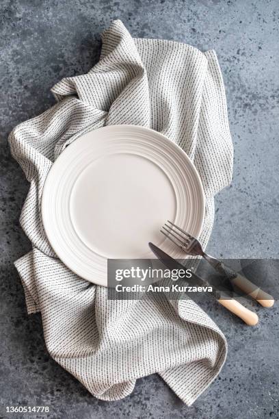 empty white plate with fork and knife on a white and black linen striped napkin folded on grey concrete background, top view. copy space - cooking utensil stock pictures, royalty-free photos & images