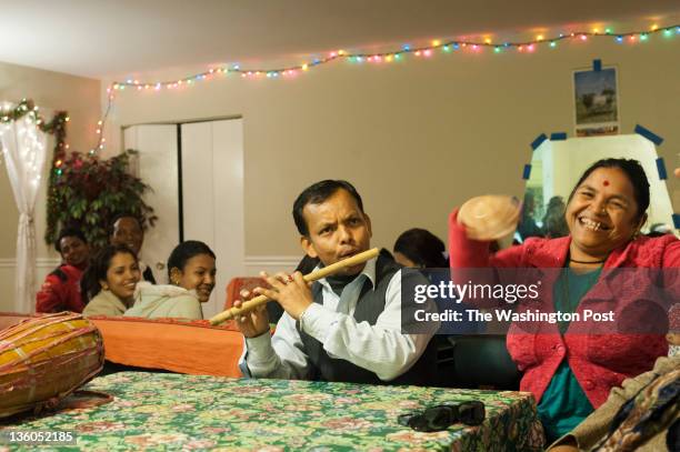 Kumar Ghataney, and Dhanmaya Gajmer , a neighbor, with family members, friends and neighbors play music and dance celebrating the second birthday of...